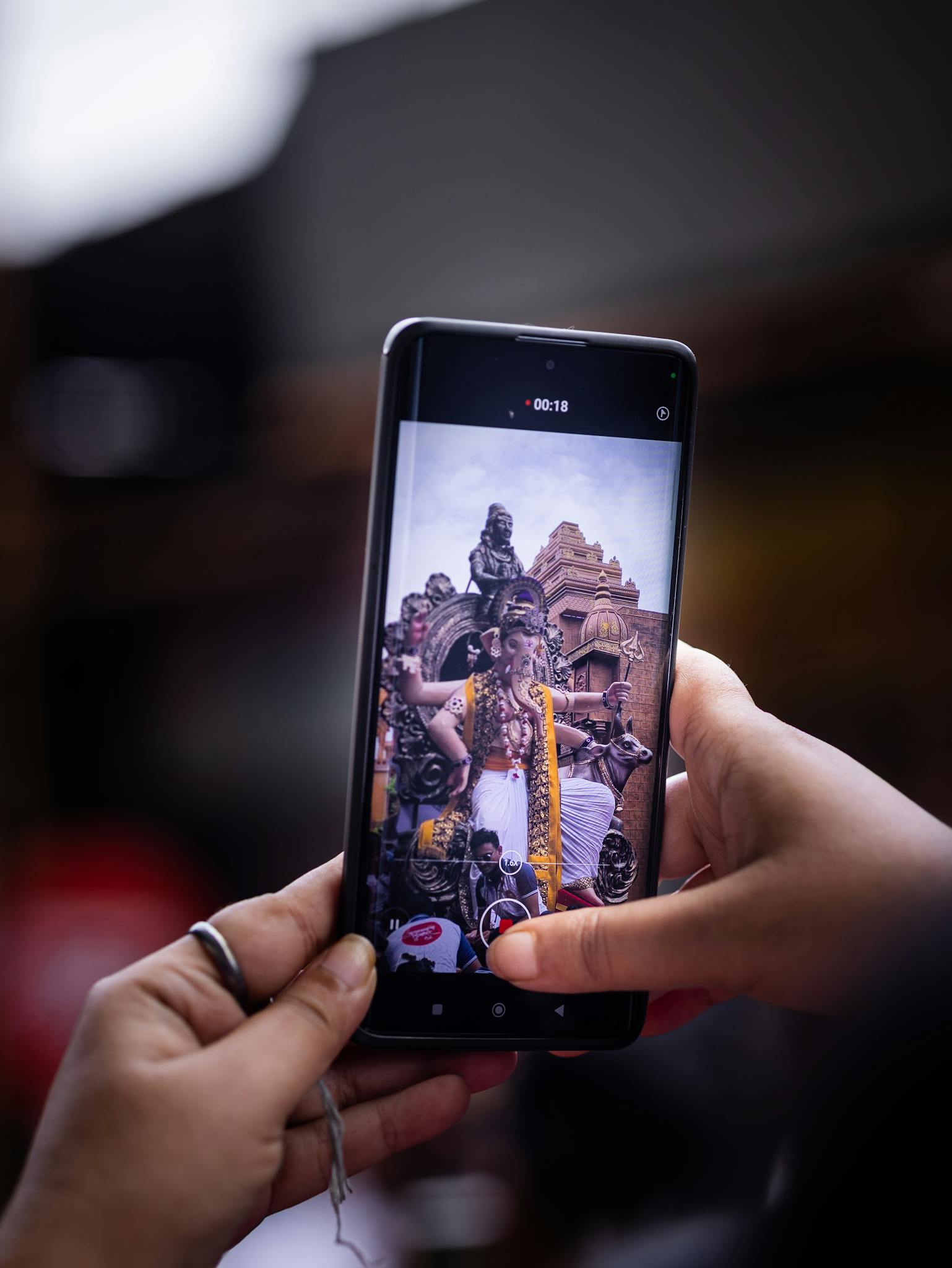 A person photographs a vibrant street festival using a smartphone.
