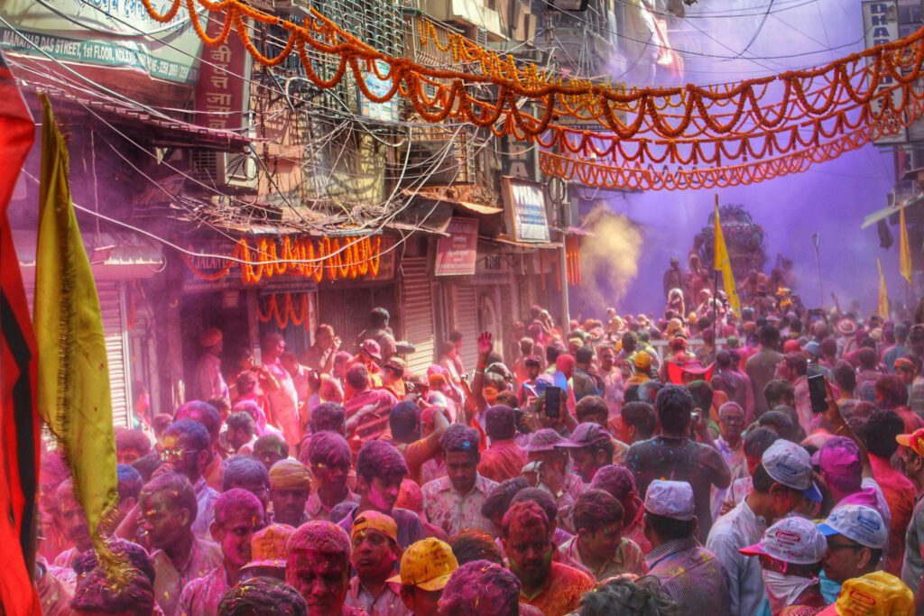 Colorful Holi festival celebration with a joyful crowd in the lively streets of Kolkata, India.
